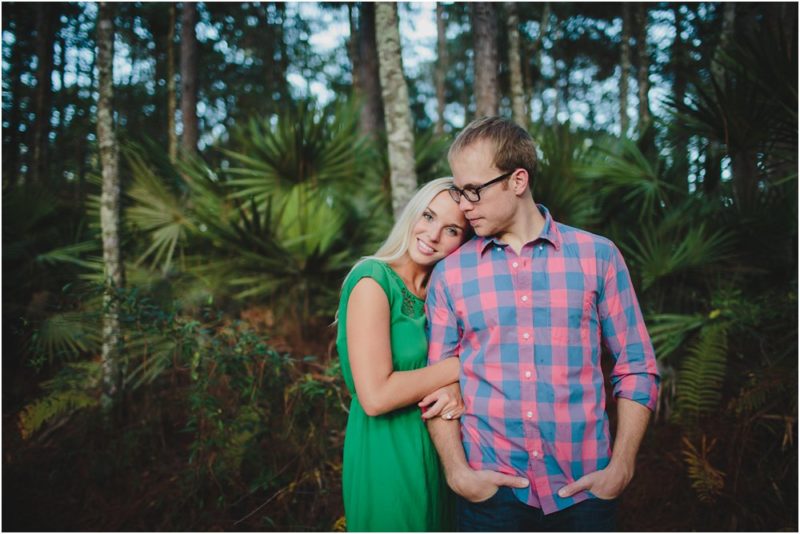 couple standing together on UNF trails with woods behind them