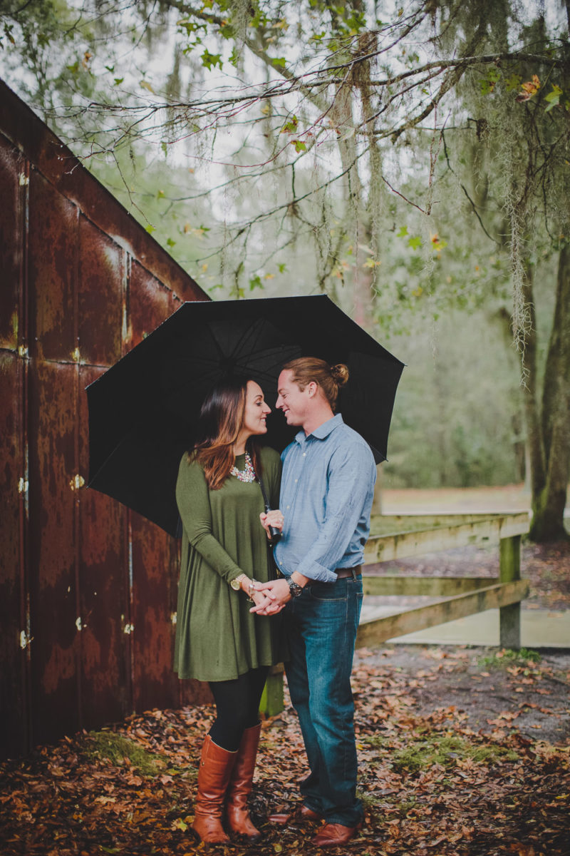 couple looking at one another under umbrella in apline groves park