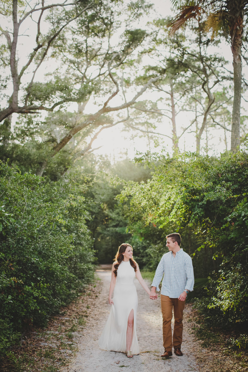couple holding hands while walking in woods