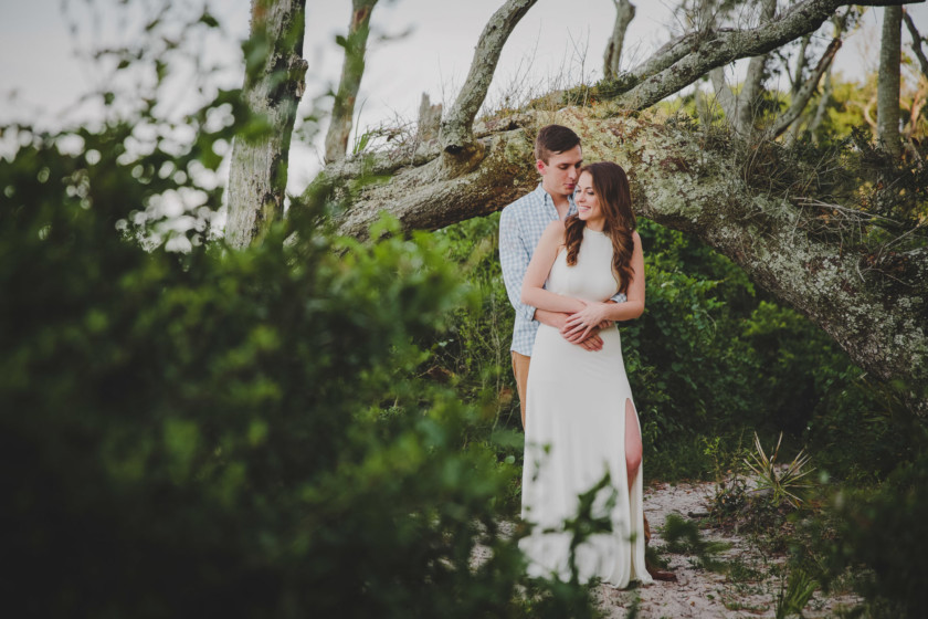 man hugging woman from behind during engagement session at big talbot island