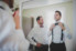 groom fixing bow tie in mirror with groomsmen looking on