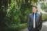 groom laughing standing in front of greenery