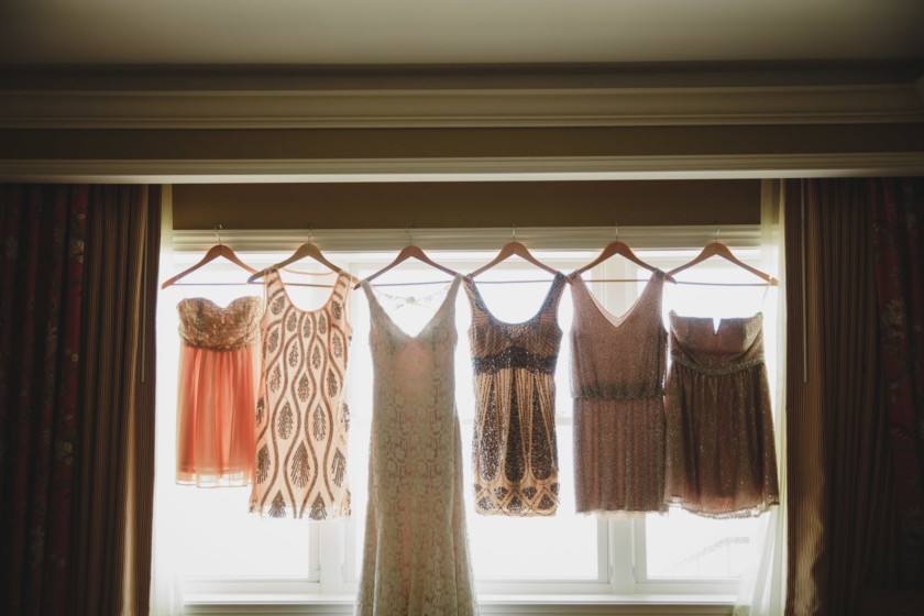 bridal gown and bridesmaid dresses hung up all together in a line