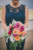 bridesmaid holding bouquet of dark pink, orange, light pink and red flowers