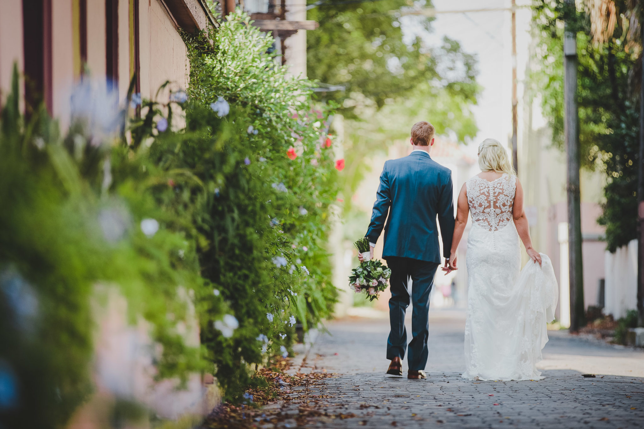 bride and groom walking down cobble street