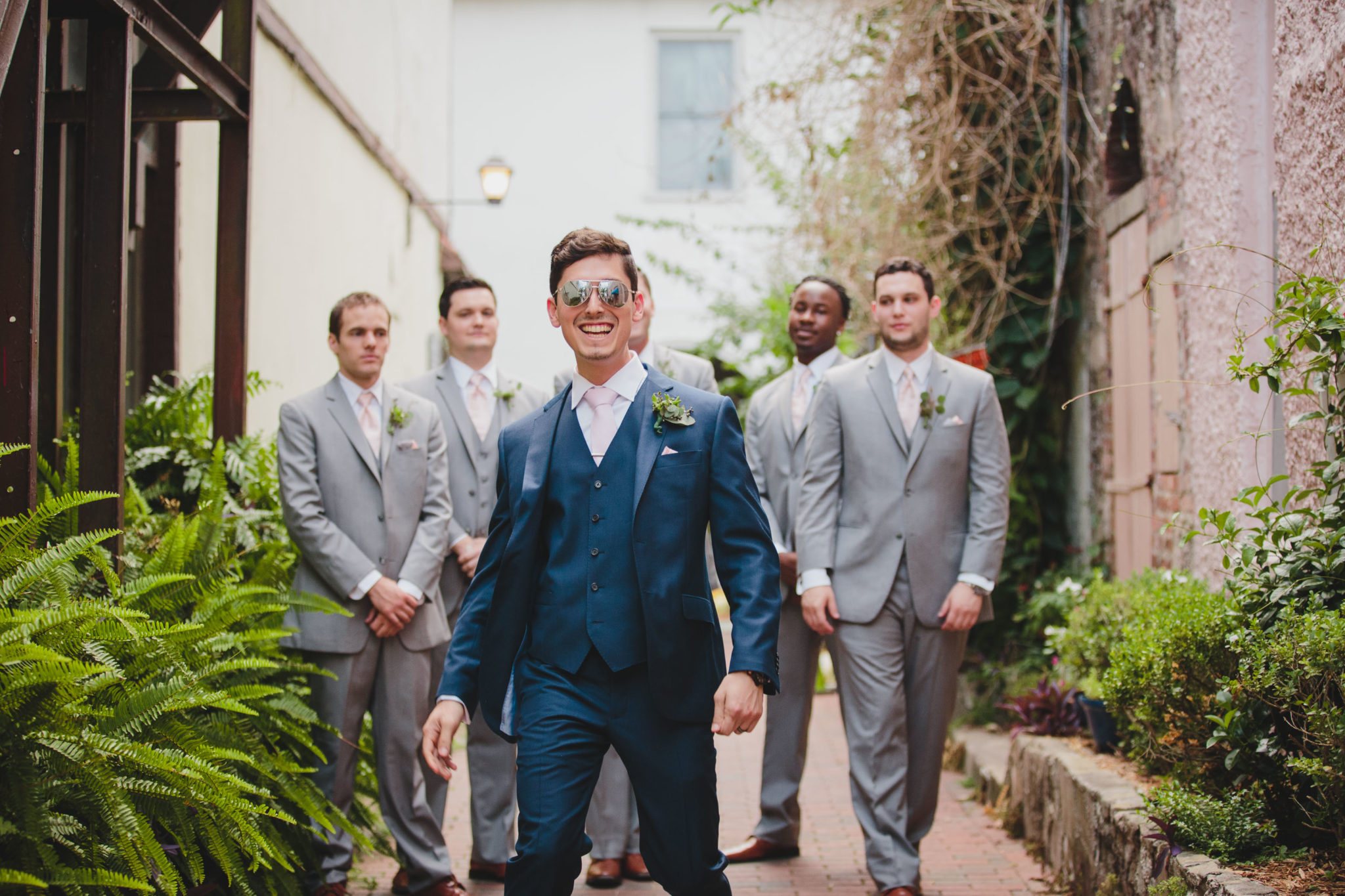 groom wearing sunglasses walking with groomsmen behind him