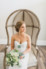 bride sitting in chair with cone back holding her all white florals bridal bouquet