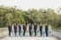 wedding party standing on bride with trees in background