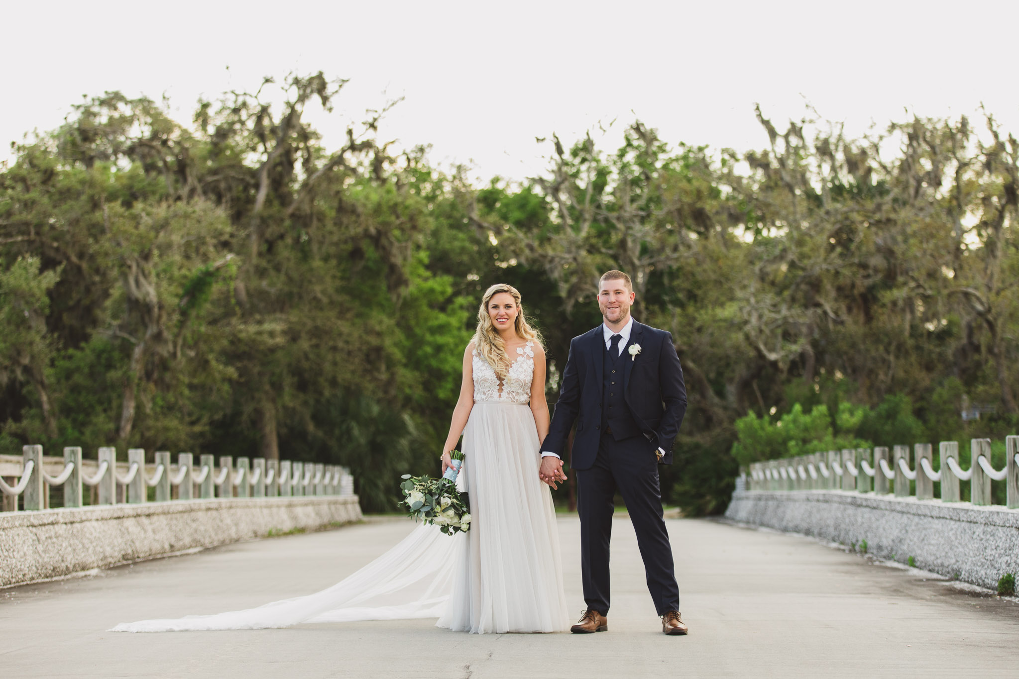 bride and groom standing in middle of road on bridge