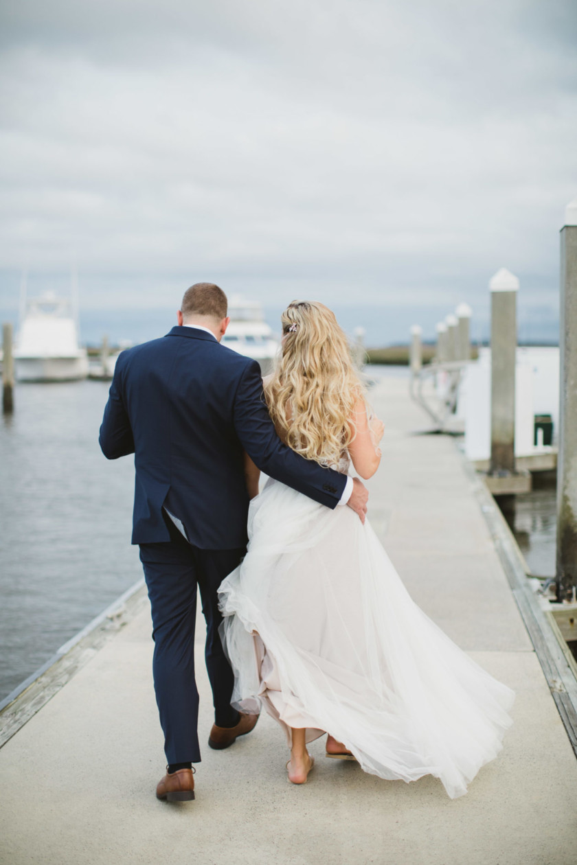 groom and bride walking away on dock