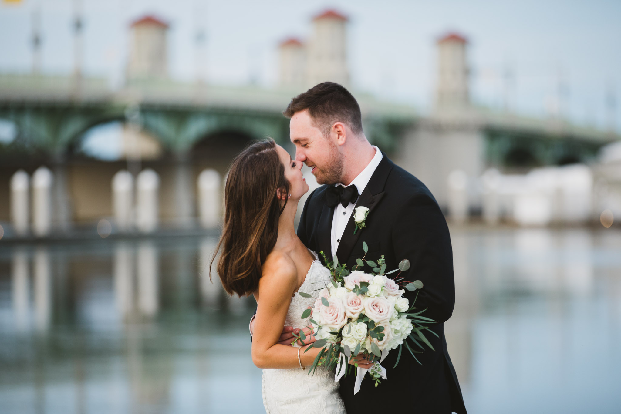 couple kissing with bridge in background