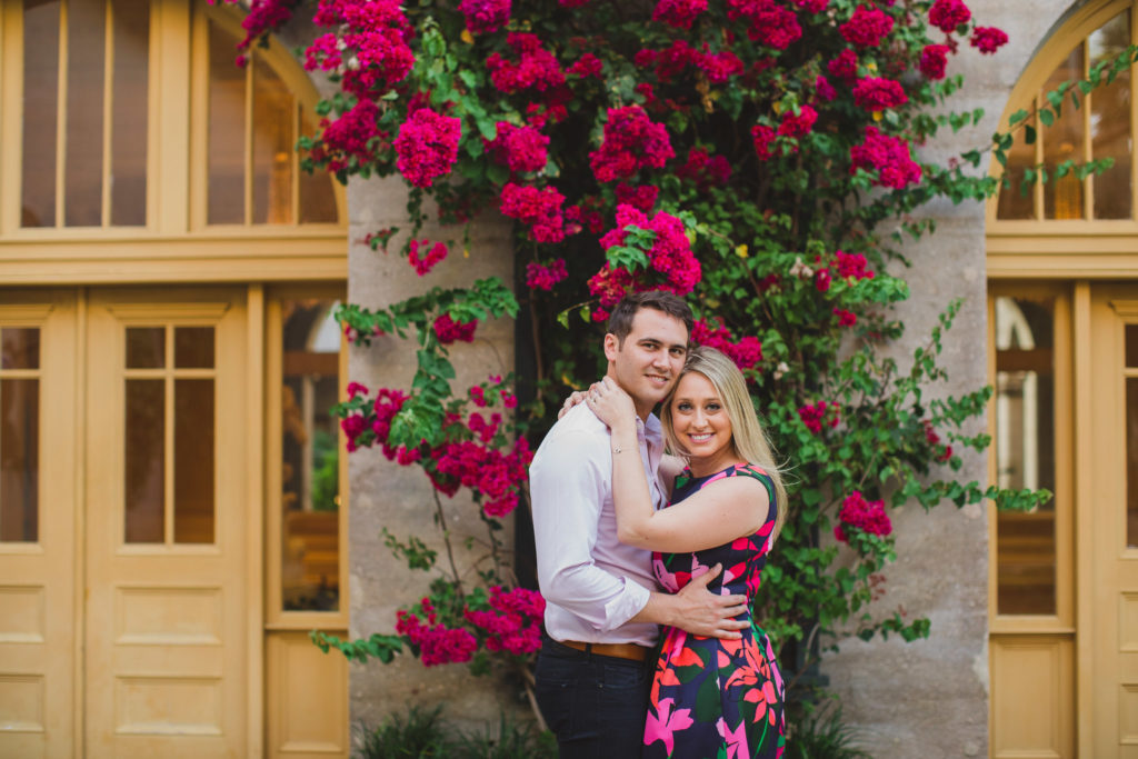 engagement session for couple with pink flowers blooming behind them