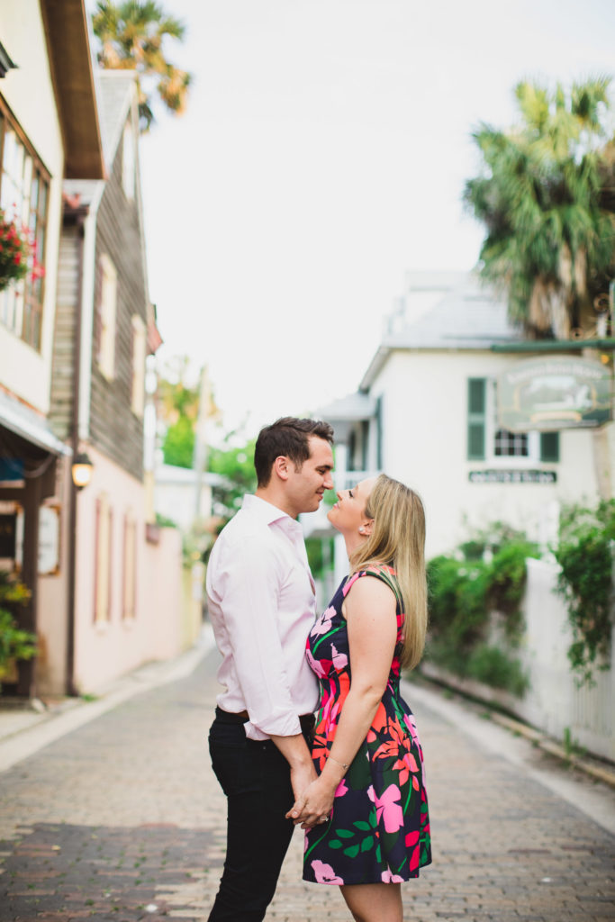 couple holding hands and kissing during engagement in st. augustine
