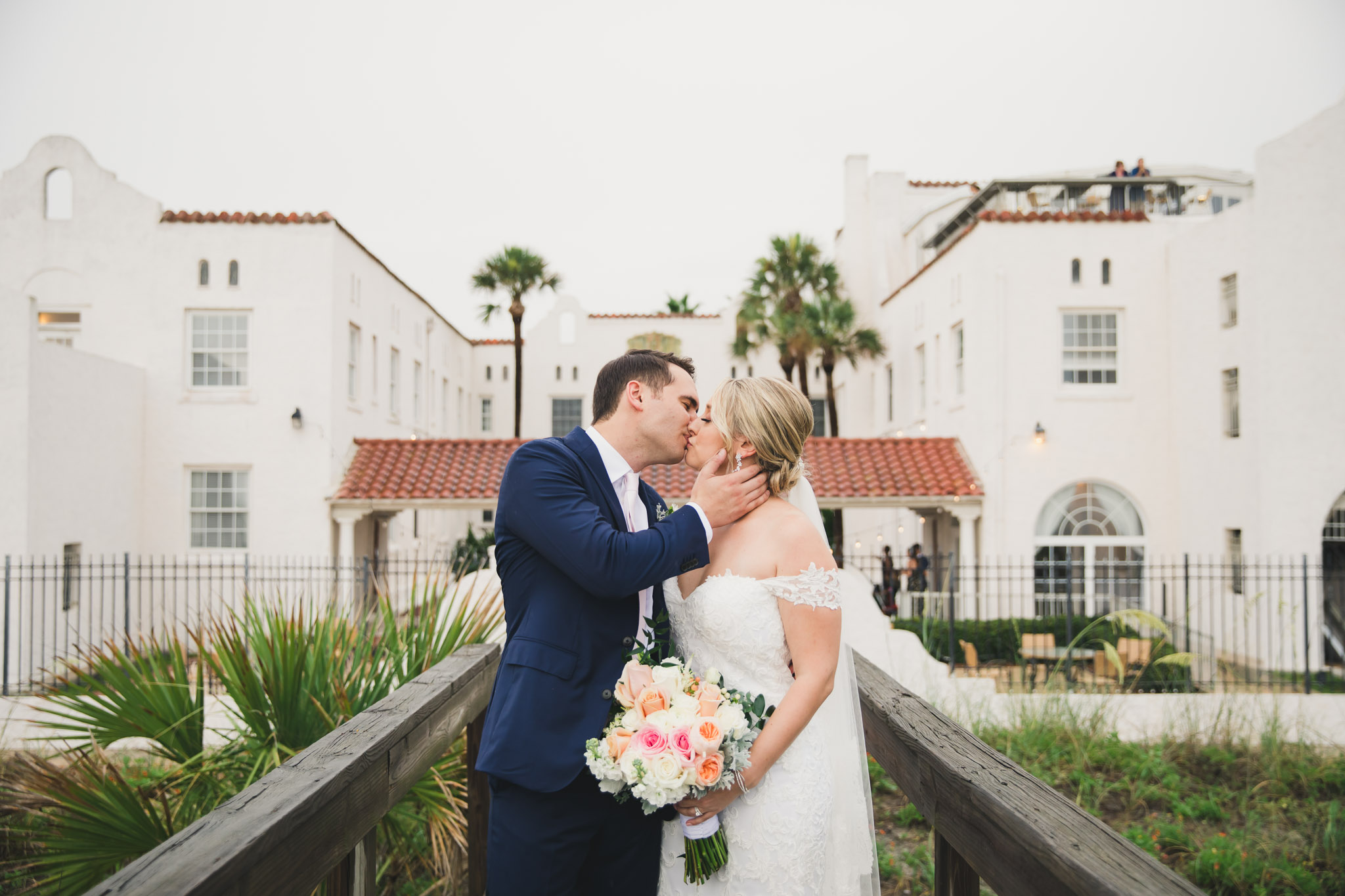 bride and groom kissing on boardwalk behind casa marina hotel in jacksonville beach