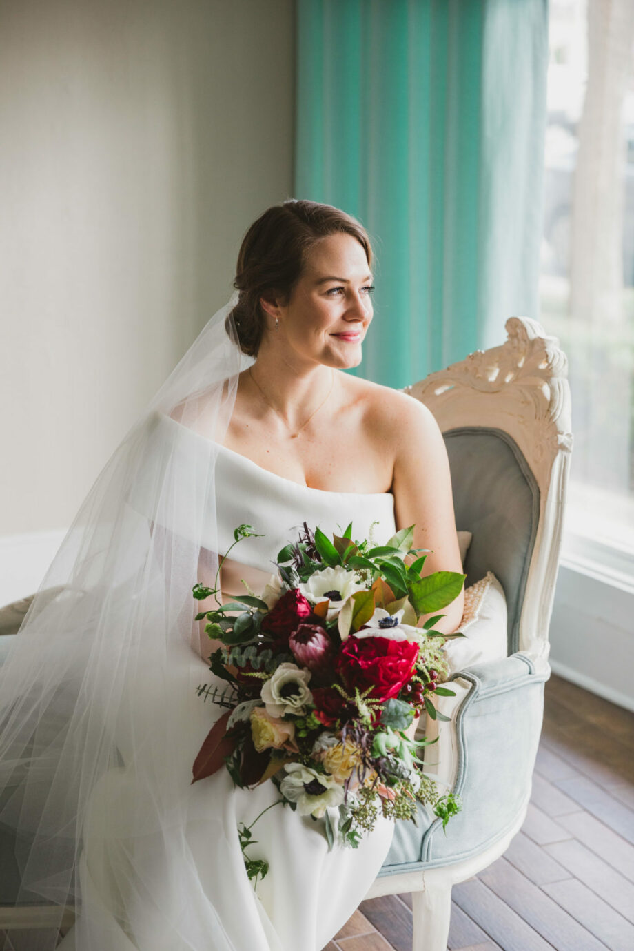 bride sitting for bridal portrait in the white room bride's holding room