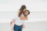 girl getting piggy back ride from man on beach during engagement session