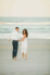 couple holding hands and running towards the ocean during sunset beach engagement