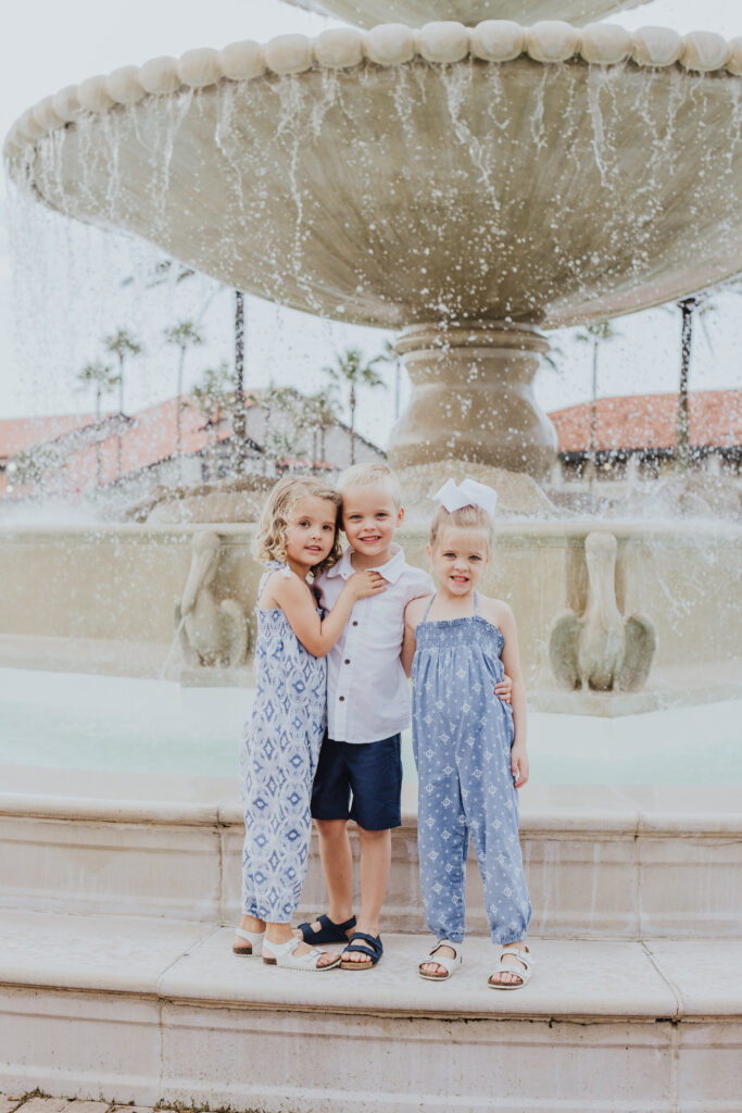 triplets standing at ponte vedra inn and club fountain with arms around each other