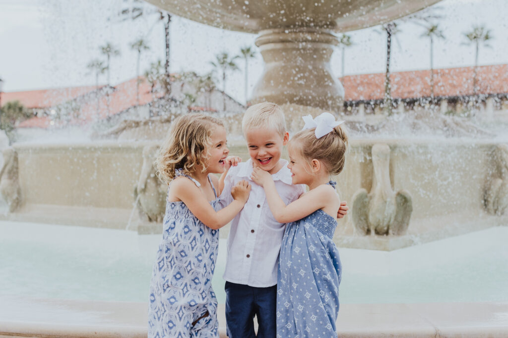triplets tickling each other standing in front of the ponte vedra inn fountain