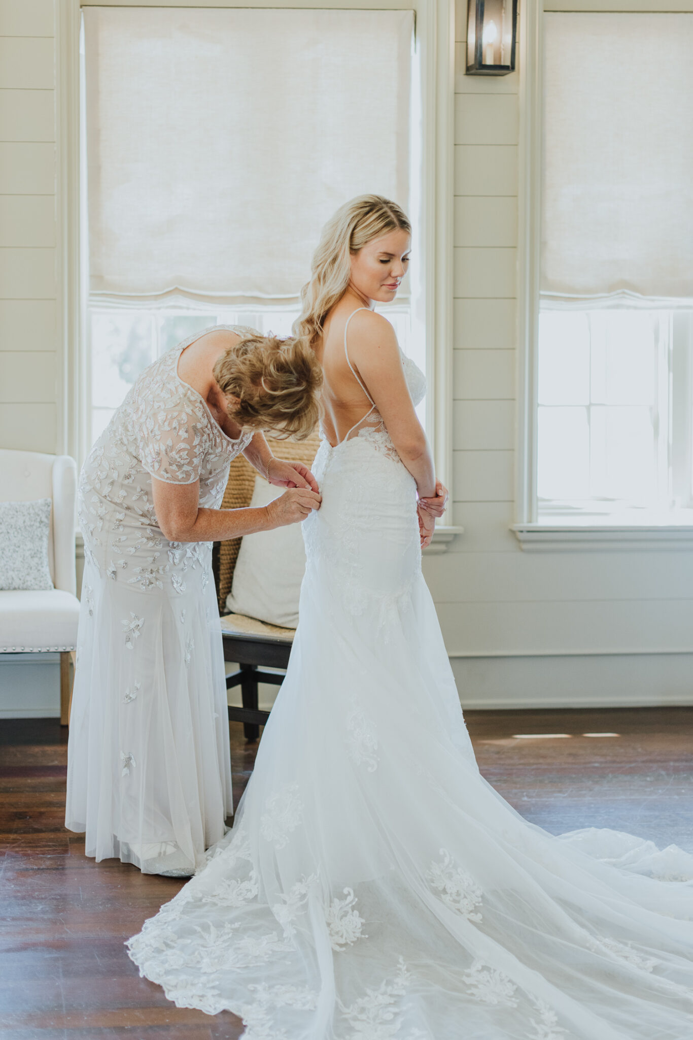 mother of bride buttoning up bride's gown as she is getting ready in the oyster bay yacht club 