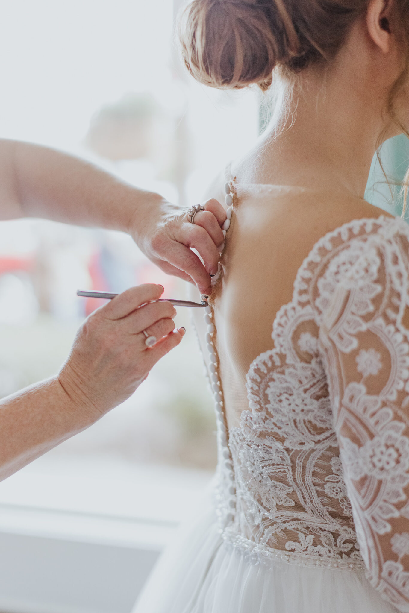 mother of bride buttoning up the bride's gown while getting ready in the grand ballroom bridal suite at the white room