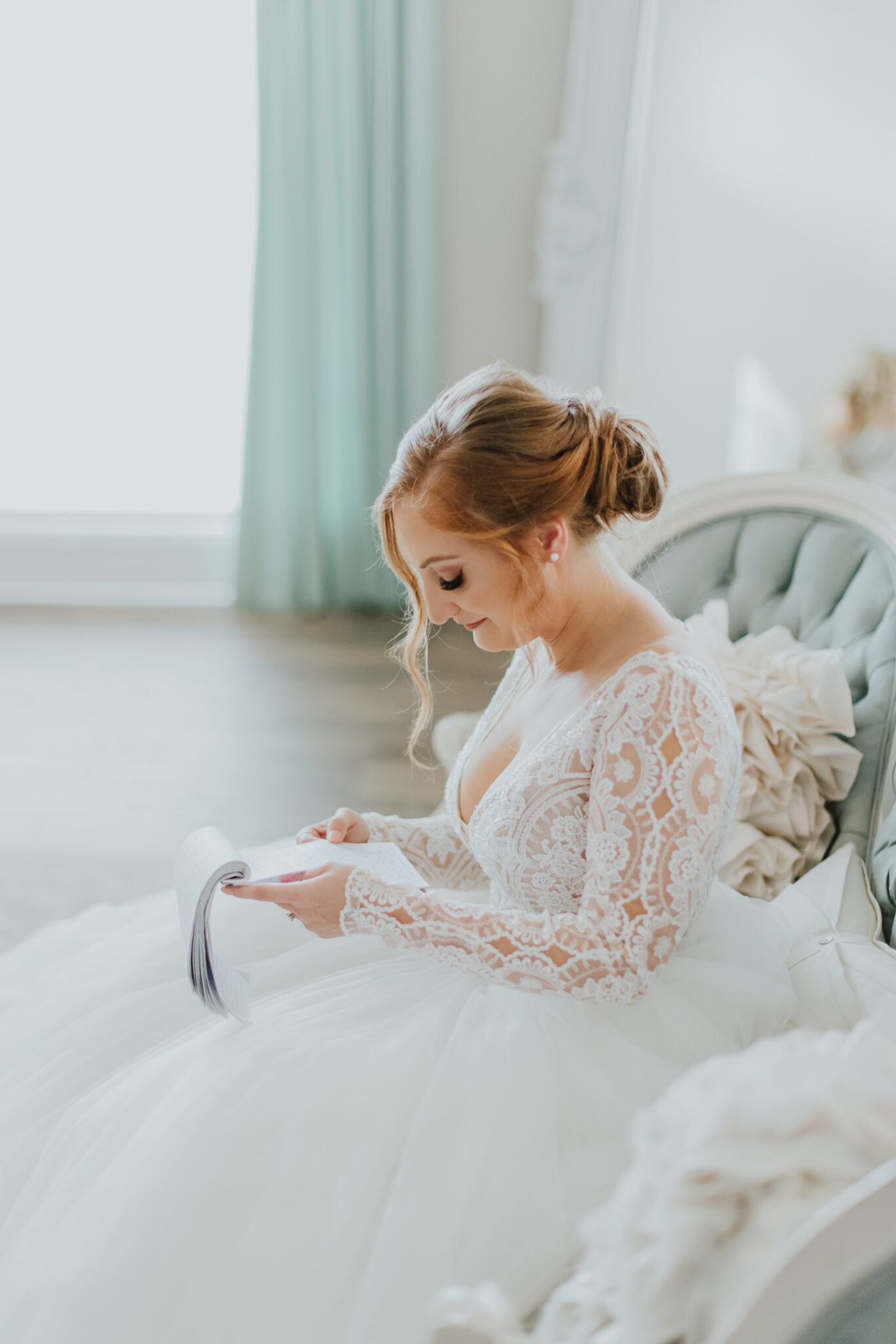 bride reading letter from the groom while sitting in the white room bridal suite