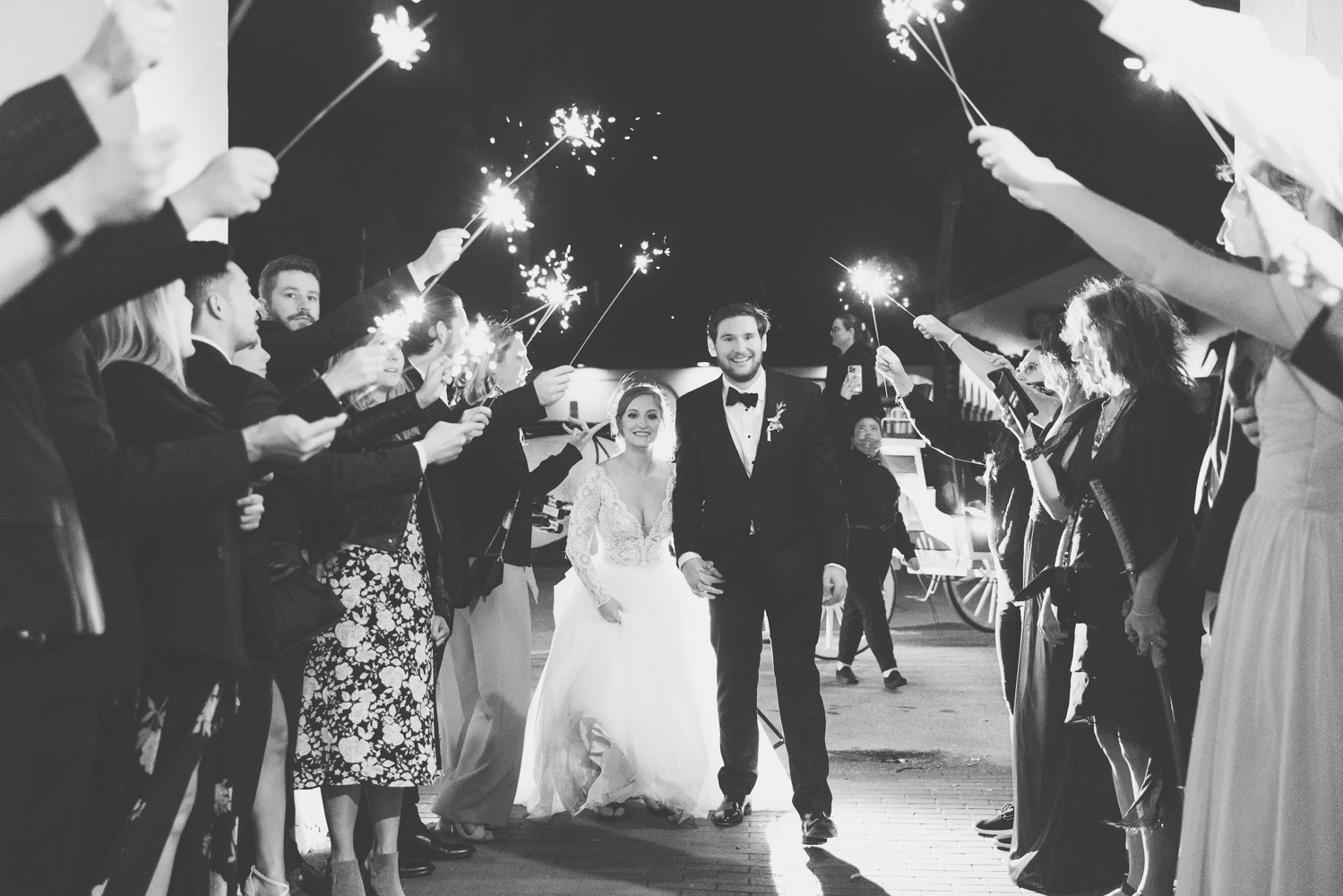 bride and groom walking down their sparkler exit at the white room wedding reception