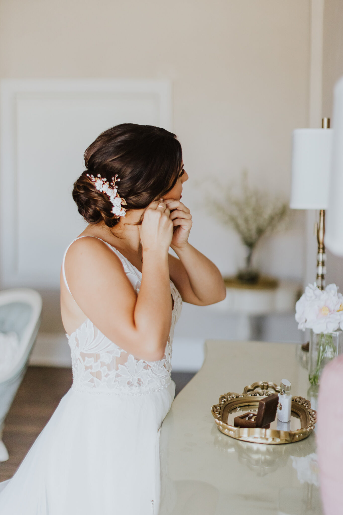 bride putting earring on while looking in mirror at the white room grand ballroom bridal suite