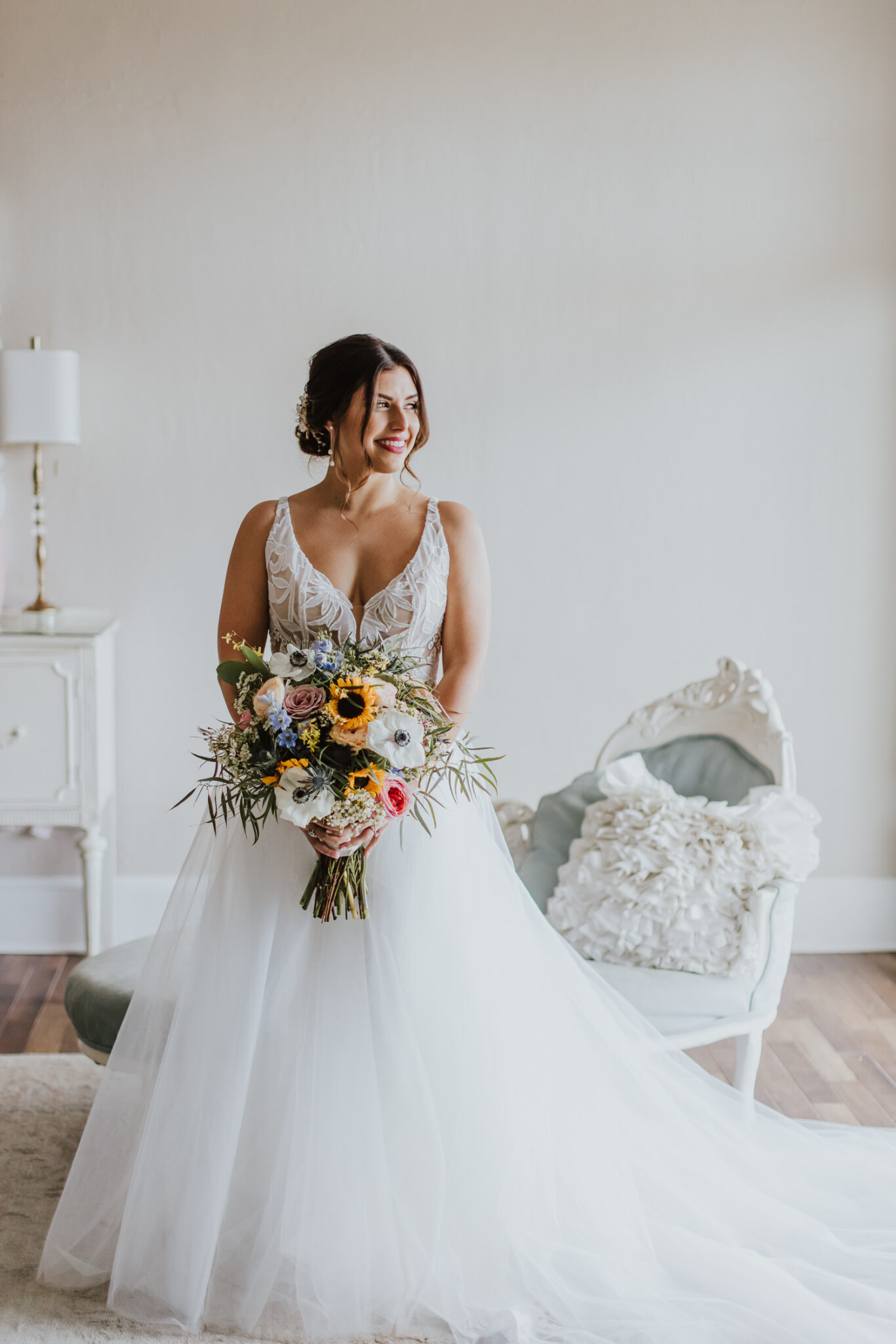 bride standing in bridal suite at the white room looking towards the window holder her bouquet