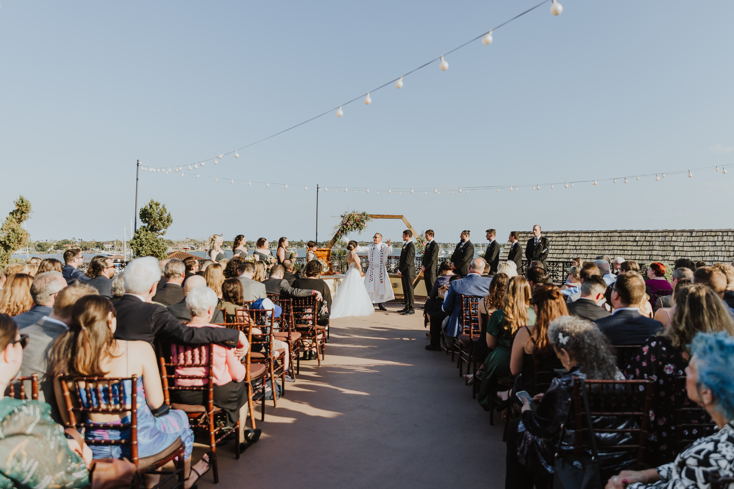 wedding ceremony on the white room rooftop with wooden hexagon arch 
