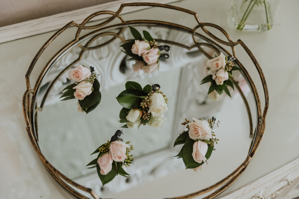 groom and groomsmen boutonnieres arranged on mirror tray in bridal suite