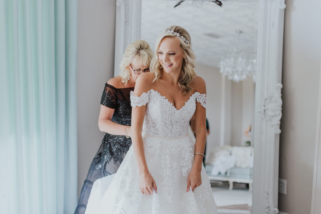 bride getting dressed zipped up by her mother in the white room bridal suite