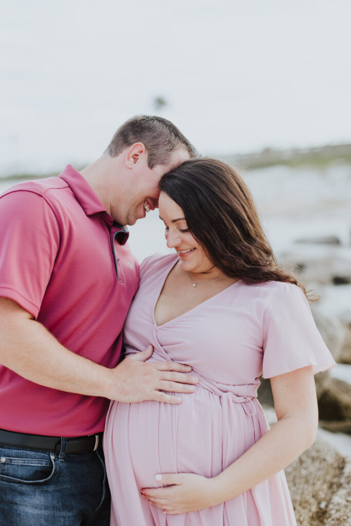 couple loving on baby belly during maternity session at beach 