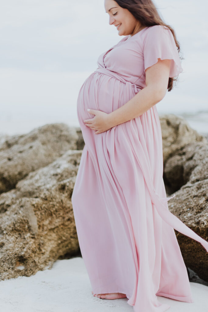 mom to be holding belly bump wearing pink flowing dress