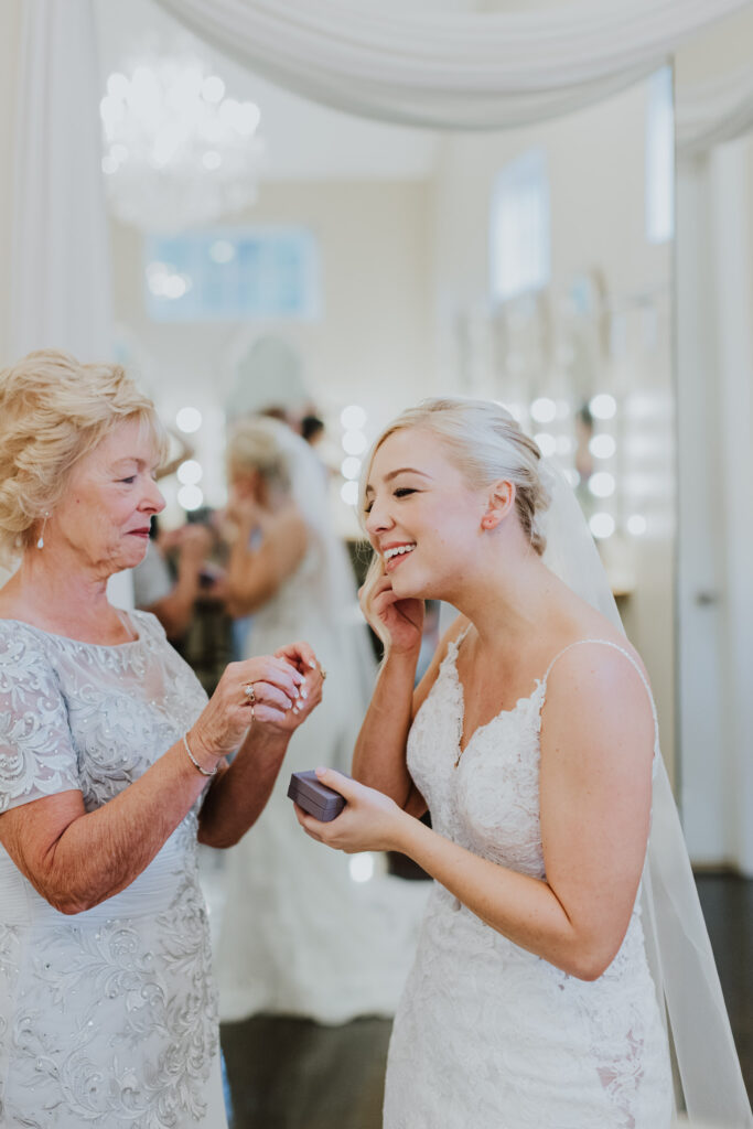 bride getting help from her grandmother to put her earring in getting ready in bridal suite of bowing oaks