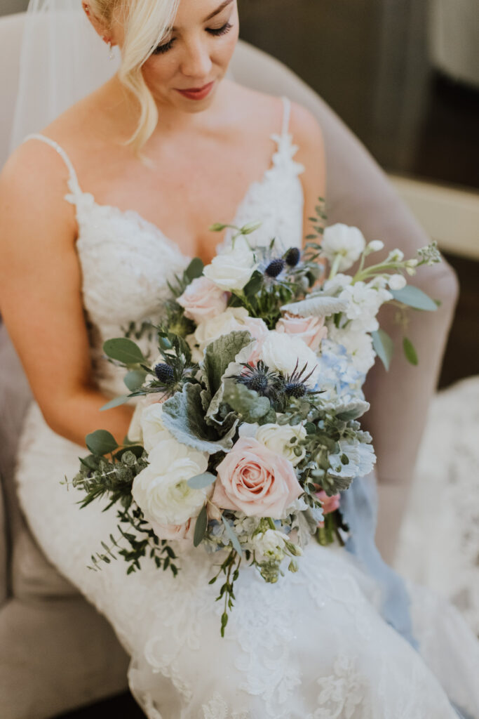 bride holding bridal bouquet of white pink and light blue florals 