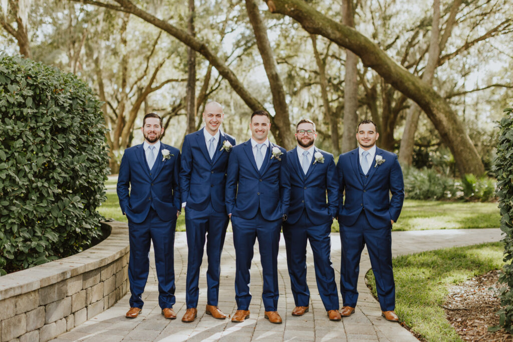 groom with groomsmen standing in path of outside of bowing oaks wedding venue