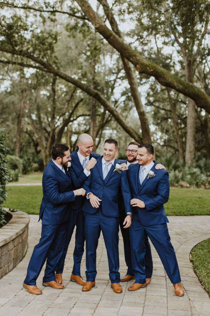 groom with groomsmen hyping him up during portraits outside bowing oaks