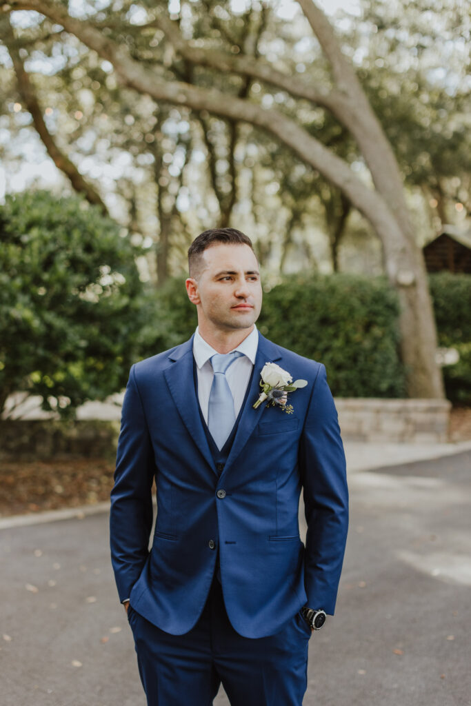 groom in navy blue suite outside bowing oaks wedding venue