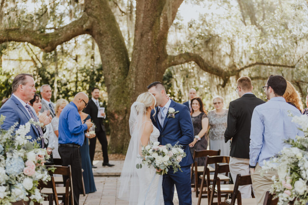 bride and groom kissing in middle of aisle of ceremony area of bowing oaks large oak tree