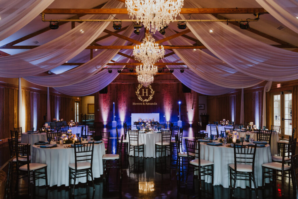 wedding reception set up at bowing oaks with dramatic uplight and white drapery