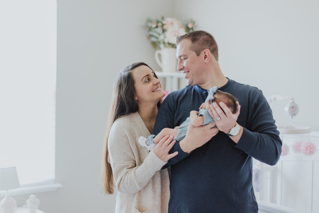 parents looking at each other while dad holds newborn baby girl 