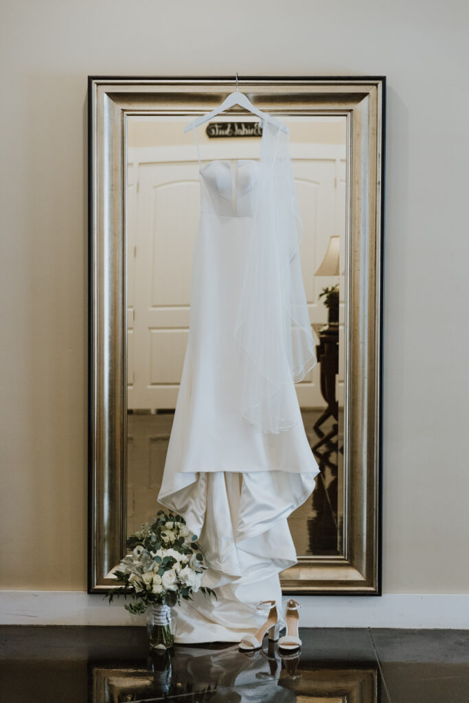 dress hanging from full length mirror outside bridal suite at bowing oaks wedding venue