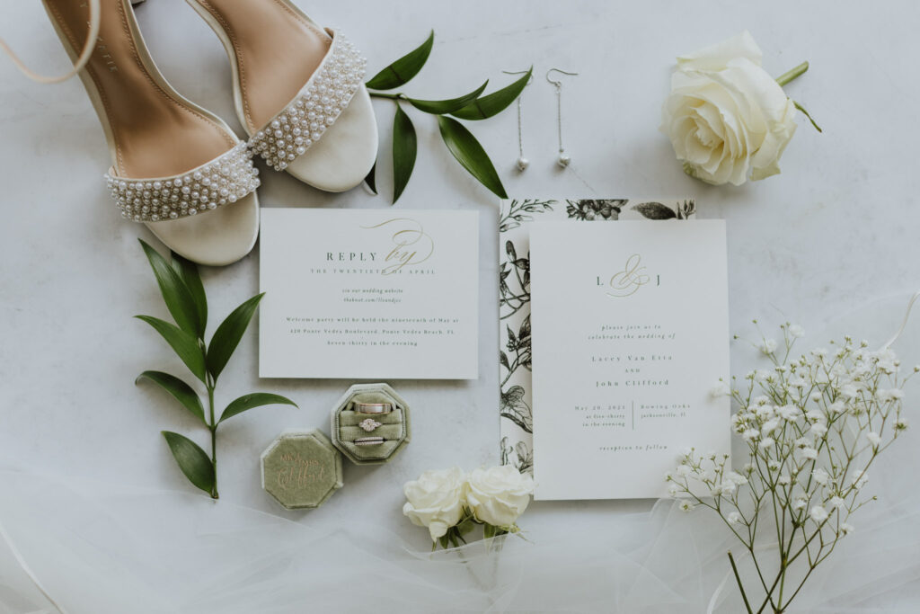 wedding invitation flat lay with white rose and pearl shoes