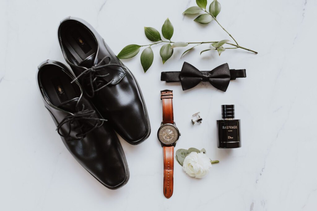 groom's details laid out with shoes, watch, boutonniere, cologne, bow tie and cufflinks
