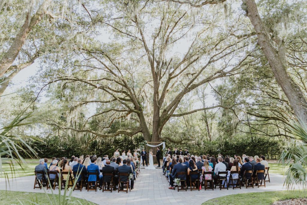 ceremony under giant oak tree with bride and groom at alter and guests sitting in seats
