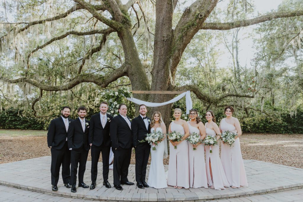 the wedding party standing together for a portrait under the large oak tree for the ceremony area 