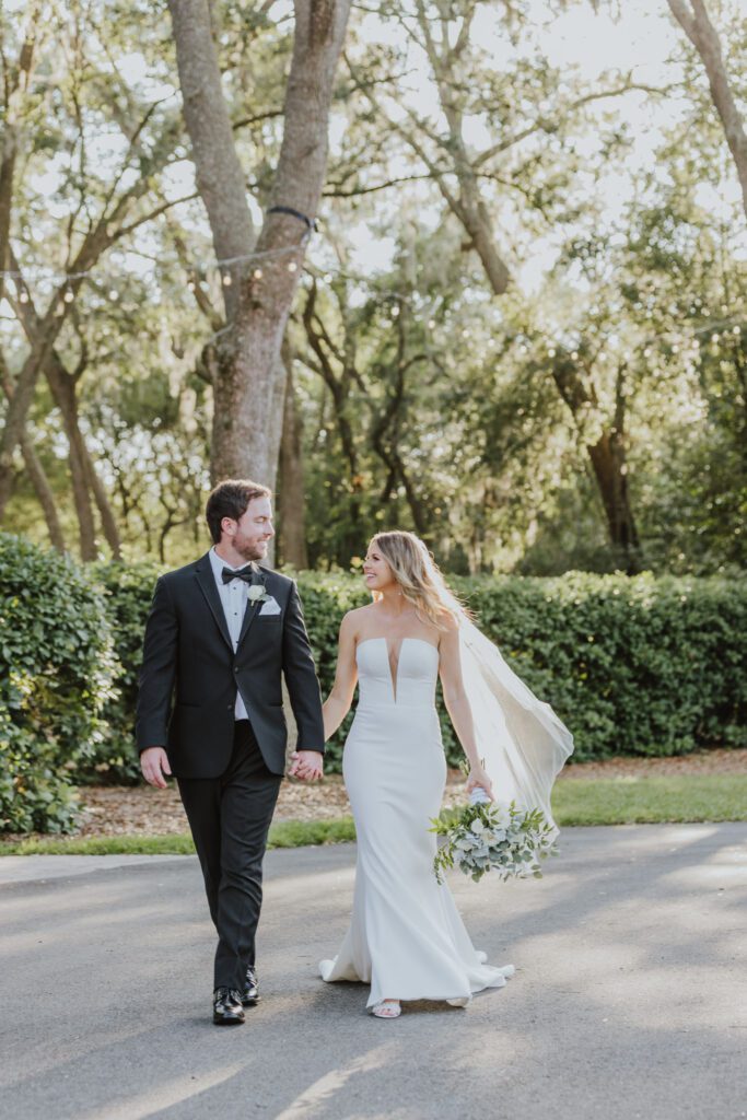 the groom and bride walking together outside of bowing oaks wedding venue