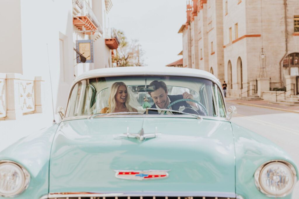 bride and groom sitting in mint green classic car on parked next to the lightner museum 