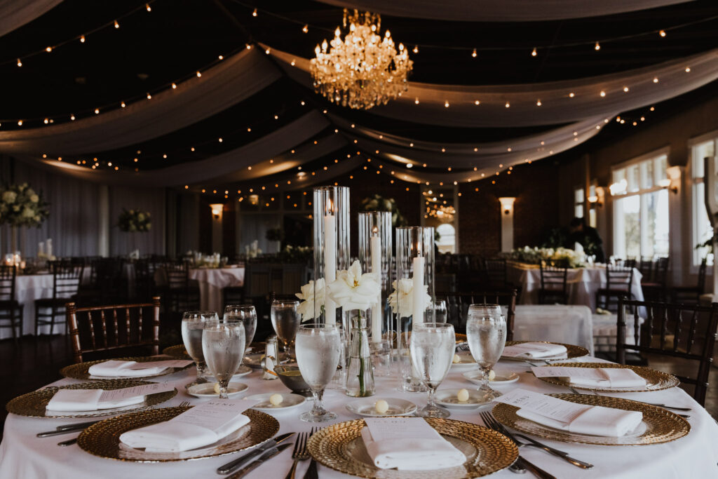 tall candles in glass and white florals in bud vases for a table centerpiece at a white room grand ballroom wedding reception
